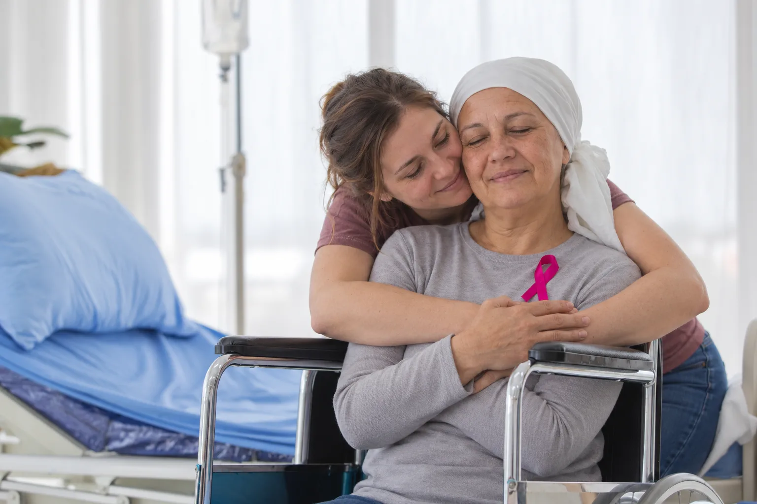 Two women sharing an embrace beside a hospital bed
