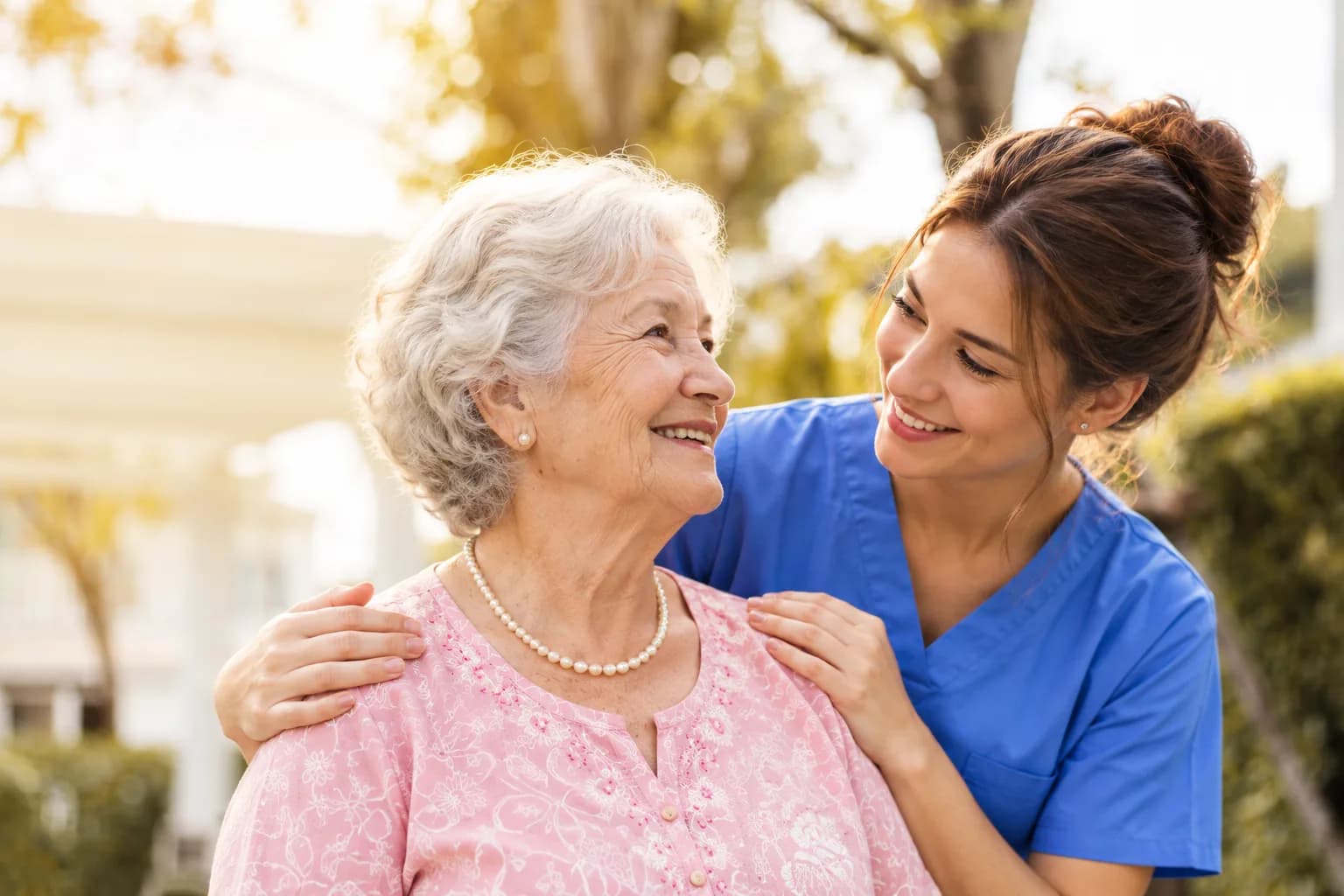 An older woman smiling with a caregiver beside her