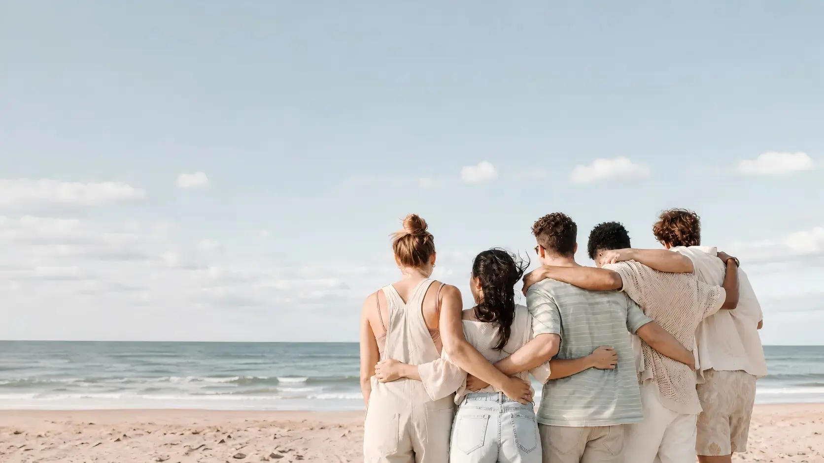 A family standing together on a beach, arms around each other